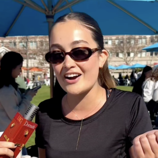 Student wearing sunglasses speaks into a microphone.